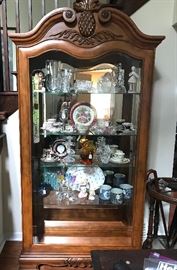 Solid wood lighted curio or hutch with glass shelves with Ornate hand-carved Pineapple accent. 