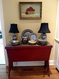 Antique red painted dough table with antique pewter plates and bowls, Chinese ceramic lamps, pottery and a framed still life of red apples in a basket