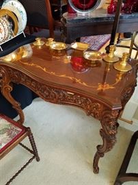 Inlaid table with pierce carved apron. Has glass over the wood top. Displaying Pickard gilt china