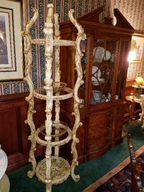 Carved and 'antiqued' 4 tier stand with glass shelves, next to a breakfront/secretary