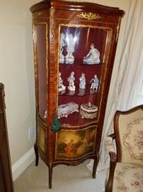 French vitrine with painted scene on lower sections.  Ormolu mounts.  Displays Capo-Di-Monte and other figurines