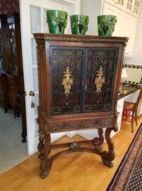 Baronial style carved cabinet. Doors are iron grills over amber glass. Note 3 matching grape motif jardinieres on top