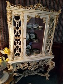 Ornate paint-decorated stand with gilt detail on the glass door