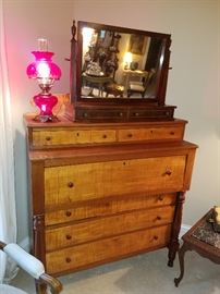 Ca. 1840 Tiger maple and cherry "Empire" chest displaying a ruby (looks pink in the photo, but is red!) lamp and a beveled shaving mirror.  Knobs on chest appear to be replacements.