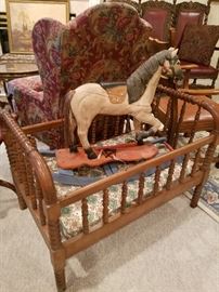 Jenny Lind style crib with a reproduction carved rocking horse in the bed