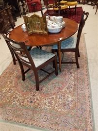 Round pine table shown with a set of 4 mahogany chairs