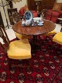 Tilt-top birdcage mahogany table shown with 4 matching shield back chairs.  Blue & white porcelain (assorted) on the table.