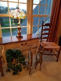 Table with stained glass lamp displayed on it.  Brass deer, Chair