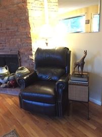 Leather Rocker Recliner, Floor Lamp, Wicker Storage Chest Stand, Bible, Leaves of Gold Poems, Giraffe Statue.