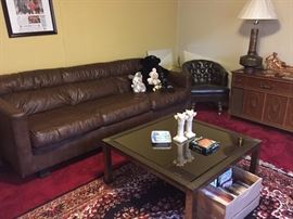 Faux Leather Sofa, Metal and Mirror Top Coffee Table, Faux Leather Tufted Barrel Back Chair on Casters