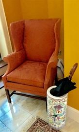 One of a pair of upholstered wing chairs in a lovely salmon fabric;  Asian pottery umbrella stand.