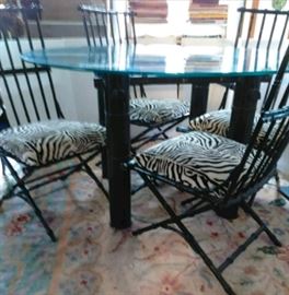 48" round wrought iron frame dinning table & 4 chairs. Glass table top & zebra print seat cushions.