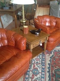 Matching curved-back orange tufted leather accent chairs; 2-level side table