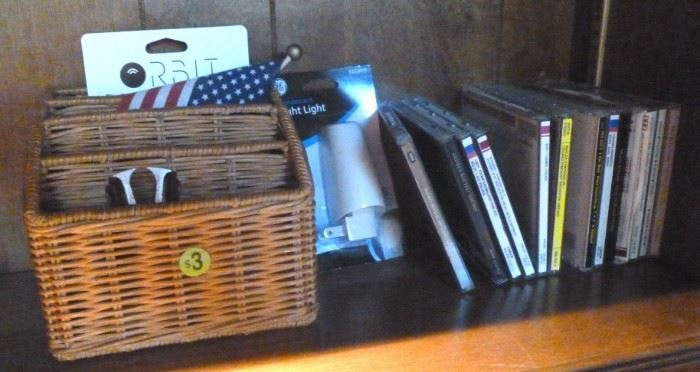 Box lot of CDs, basket, and orbit key finder
