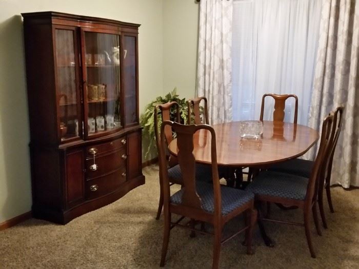 The oval cherry dining table has two leaves.  It is shown with one of the leaves installed.  There are six Queen Anne style cherry dining chairs.  The vintage china cabinet is made of mahogany.