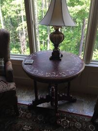 This is an elegant round table that is painted in the predominant colors of brown/maroon and gold. Notice its unusual and decorative base and feet.  The lamp is not included. Price for the table only: $200.