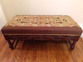 Renaissance Revival upholstered bench, late 19th cent., of rectangular form, the seat upholstered in floral needlepoint on a chocolate ground, with brass nailhead trim, above block and turned legs joined by a pierced carved scrollwork front stretcher; measures 17"h x 39"l x 18"w.