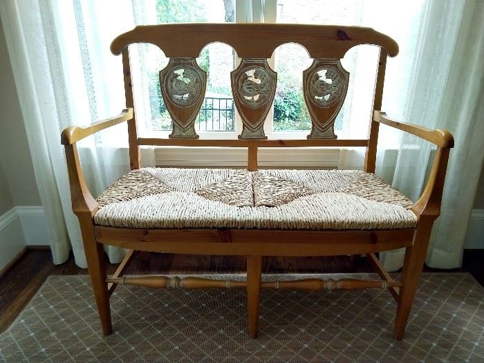 French Provincial style carved pine bench, with shaed back and woven rush seat; measures 40" h x 43.5"l x 18.5"d.