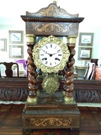 Late 19th century rosewood Empire style portico clock, the crest and base marquetry inlaid and supported by four spiral twist columns with gilt bronze capitals; measures 17"h x 9"w x 5"d.