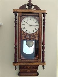 19th century Continental marquetry inlaid regulator clock, with a carved leaf pediment above the clock face, flanked by turned pilasters, terminating in an inlaid scroll-link base; measures 38.5"h x 15"w x 5.5"d.