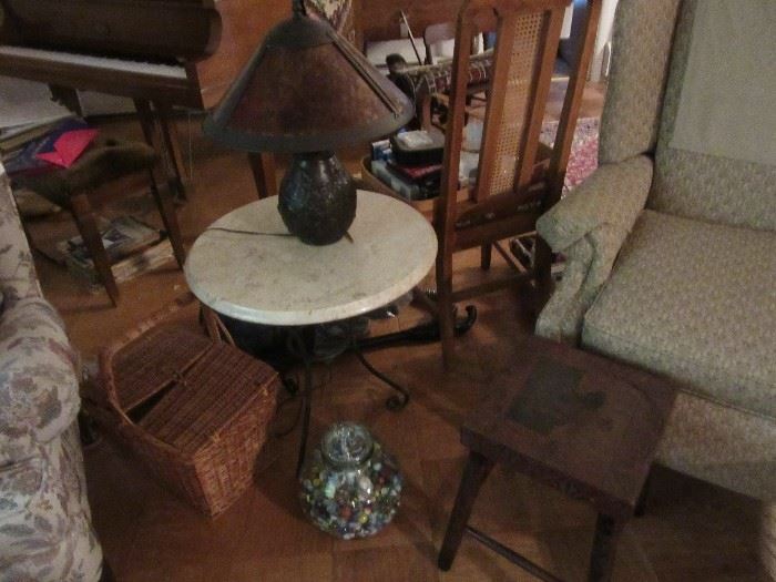 Marble top table with cast iron legs .    The carved table next to the marble table is carved on top and legs. The jar is filled with early marbles, and the Lamp is metal 