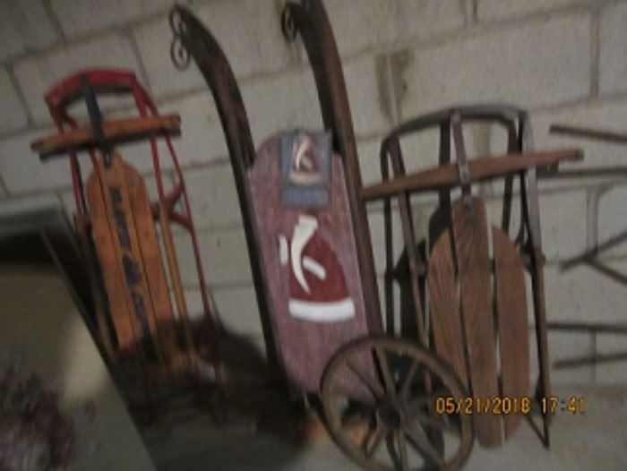 The sled on the left is a newer sled. The middle sled is an early sled as is the one on the right. The wheel is from an early wagon. 
