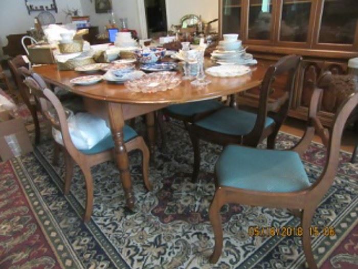 The cherry dining table has 4 leaves and without the leaves the table is small.  There are 8  carved crest chairs.  The dining room also contains a glass top table and wicker chairs.  