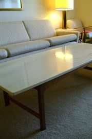 Unusual Corian topped teak coffee table measures 61 by 23.