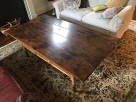 Antique farm table repurposed as a coffee table on a vintage oriental rug.