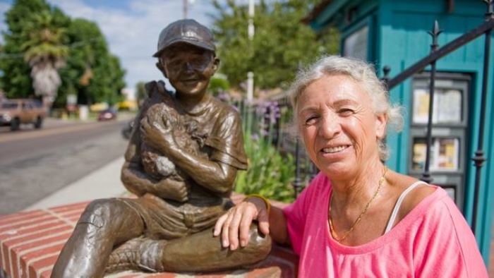 Artist Célou  Bonnet is pictured with her bronze sculpture, "Bonjour", in the Fallbrook Village Square. The piece was donated to the community as  "Art in Public Places" by the Fallbrook Village Rotary.  The name represents both the friendly images associated with Fallbrook, and also the love a new citizen has in her heart for her adopted country.