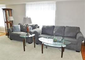 Like new gray sofa and love seat from Ashley Furniture. Like new glass top coffee table and two end tables. 