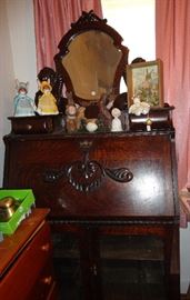 Antique bureau with desk, mirror and glass front cabinet below.