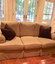 One of two identical light tan sofas in pristine condition