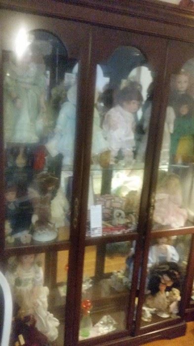 3 door curio cabinet with several dolls