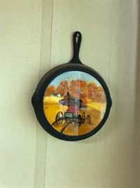 Folk art painted cast iron skillet and 3 handpainted saws as well as lots of other unique home decor and wall art.