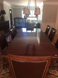 Pristine Dining room table with two leaves and 8 wood and leather arm chairs.