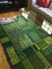 Custom glass table.   Greens area rug.