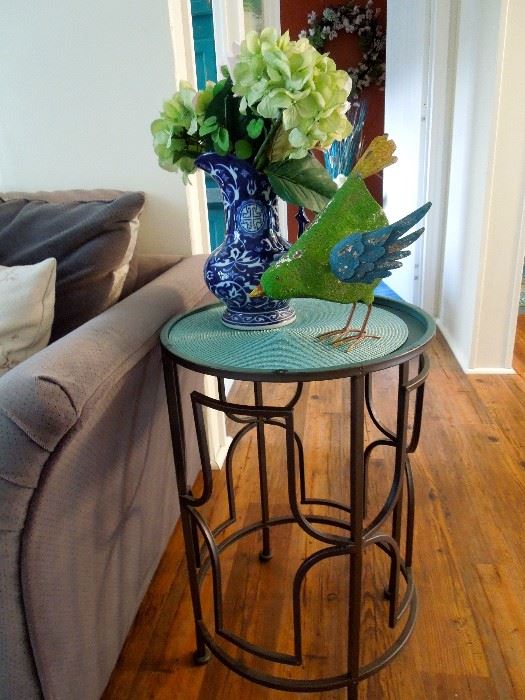 Metal side table. Painted metal bird sculpture and cobalt blue decorative vase with floral arrangment