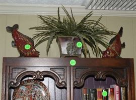 Some ceramic fish on top of the bookcase.