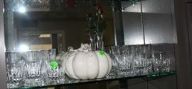 More glasses on glass shelf with white pumpkin.