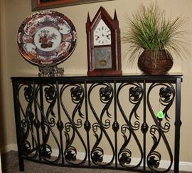 The metal table in the upstairs foyer with wood top.  Also includes a beautiful antique clock, large round oriental plate (beautiful) and another silk plant in basket.