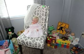 Another doll sitting in pretty chair to match comforters and with her other toys.