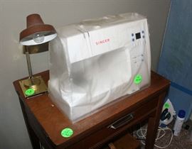 Portable Singer sewing machine and one in a wood cabinet.