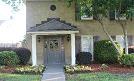 The front of the house with the beautiful landscaped yard and the flowers and shrubbery.
