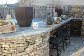 The kitchen area outside with metal bar stools.