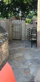 The side gate from front yard.  Has 2 wood racks with some fire wood on them.