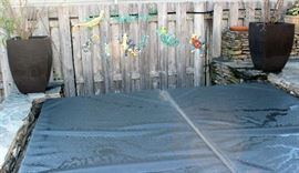The top of the hot tub with cover and metal items on fence with flower pots on side.  Has steps leading up to the hot top.  Holds 6 people.
