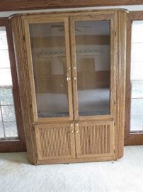 Solid oak gun cabinet with storage. Holds 12 long guns; locking for both upper display and lower shelves and drawers. Has internal lighting.