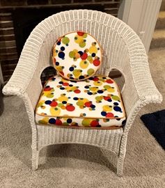 Wicker chair with bright upholstered cushion and matching cushion.