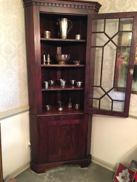 Antique corner cabinet with doors open. Dates to late 1800's. Excellent condition. Silverplate and sterling on shelves.